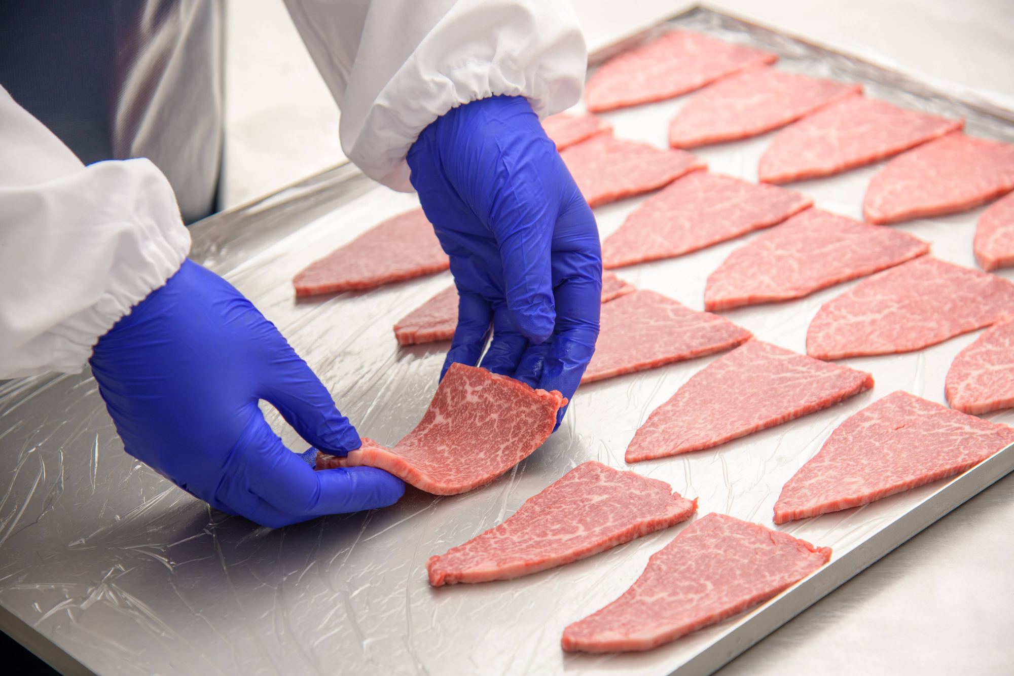切り分けた肉をトレーに並べる手元
